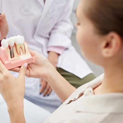 A dentist showing a dental implant model to his patient