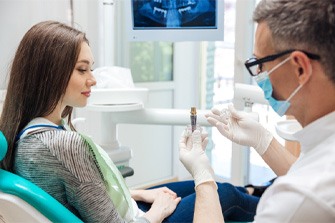 A male dentist showing his female patient a dental implant