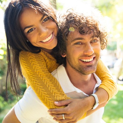 Young couple with white teeth smiling outside