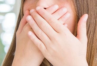 Patient with lost dental crown covering smile