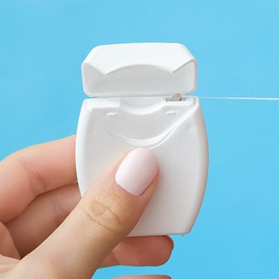 Person holding floss to help prevent dental emergencies
