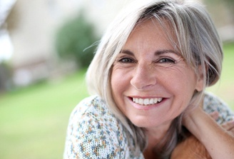 Senior woman with dental implants San Marcos, CA sitting outside and smiling