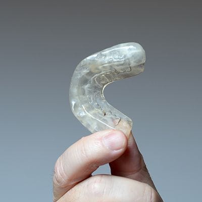 Hand holding clear nightguard for bruxism