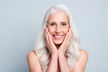 An older smiling woman happy with her new dental implant