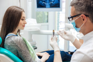 Dentist showing woman dental implant model