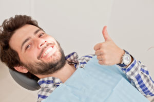man smiling while sitting in dental chair