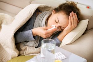 A woman sick laying on a couch.