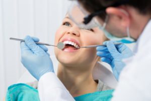 woman smiling while receiving dental checkup