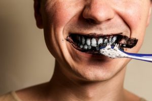 person brushing their teeth with activated charcoal 