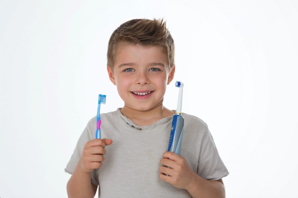 Boy holding manual and electric toothbrush