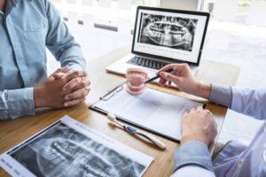 Dentist and patient sitting at a desk discussing an X-ray and dental issues