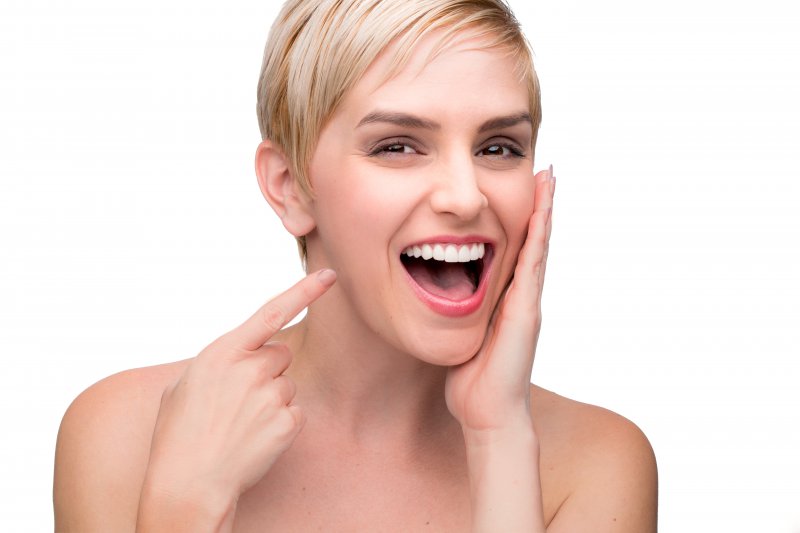 Woman pointing at her new smile from a cosmetic dentist.