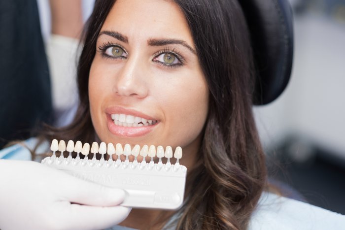 A dentist comparing temporary veneers to a patient’s smile.