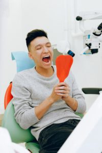 Man looking at teeth in dental mirror