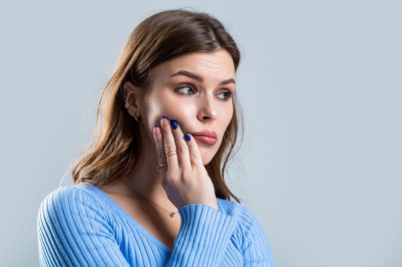 Young woman holding her cheek in pain