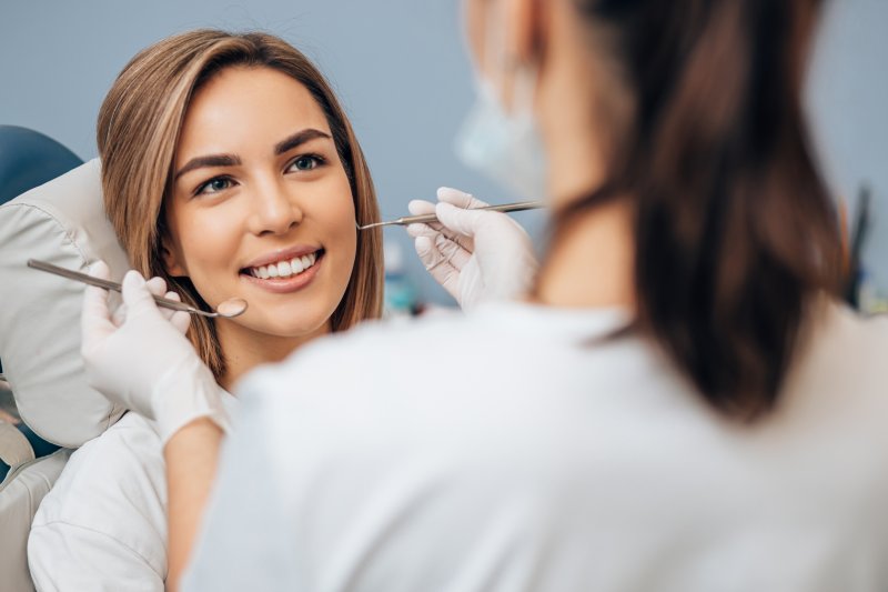 Woman smiling at her dentist as her dentist holds up some tools to either side of her face