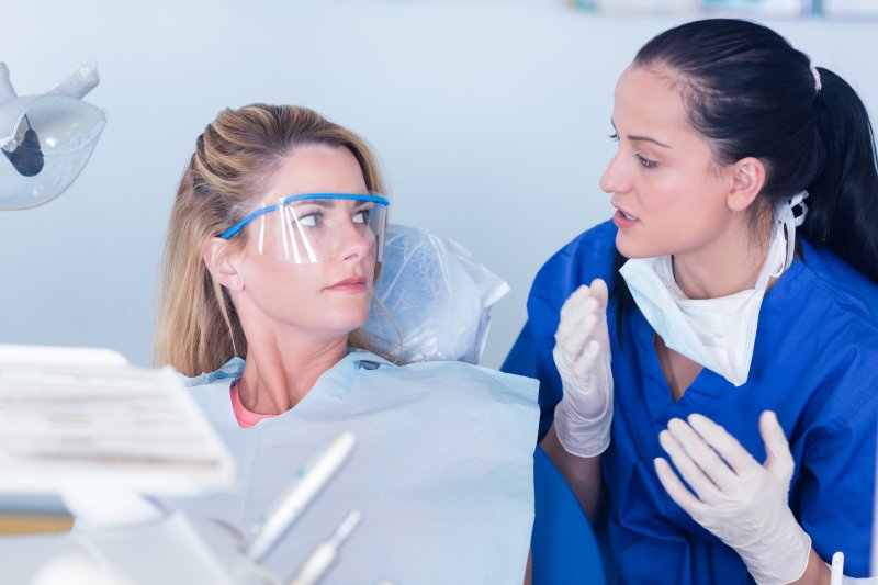  dentist talking to patient about bump on gums