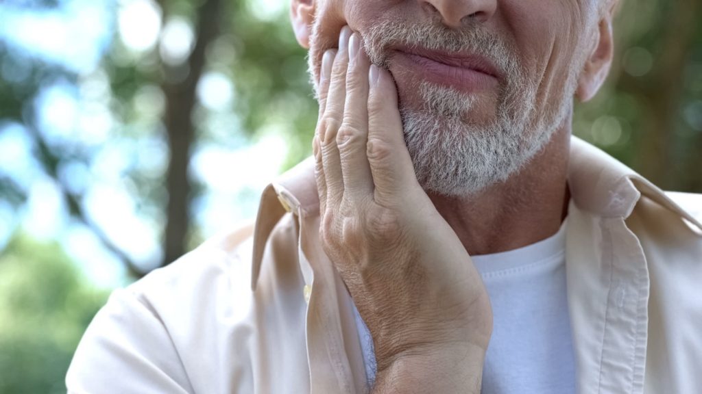 patient suffering from teeth grinding holding cheek